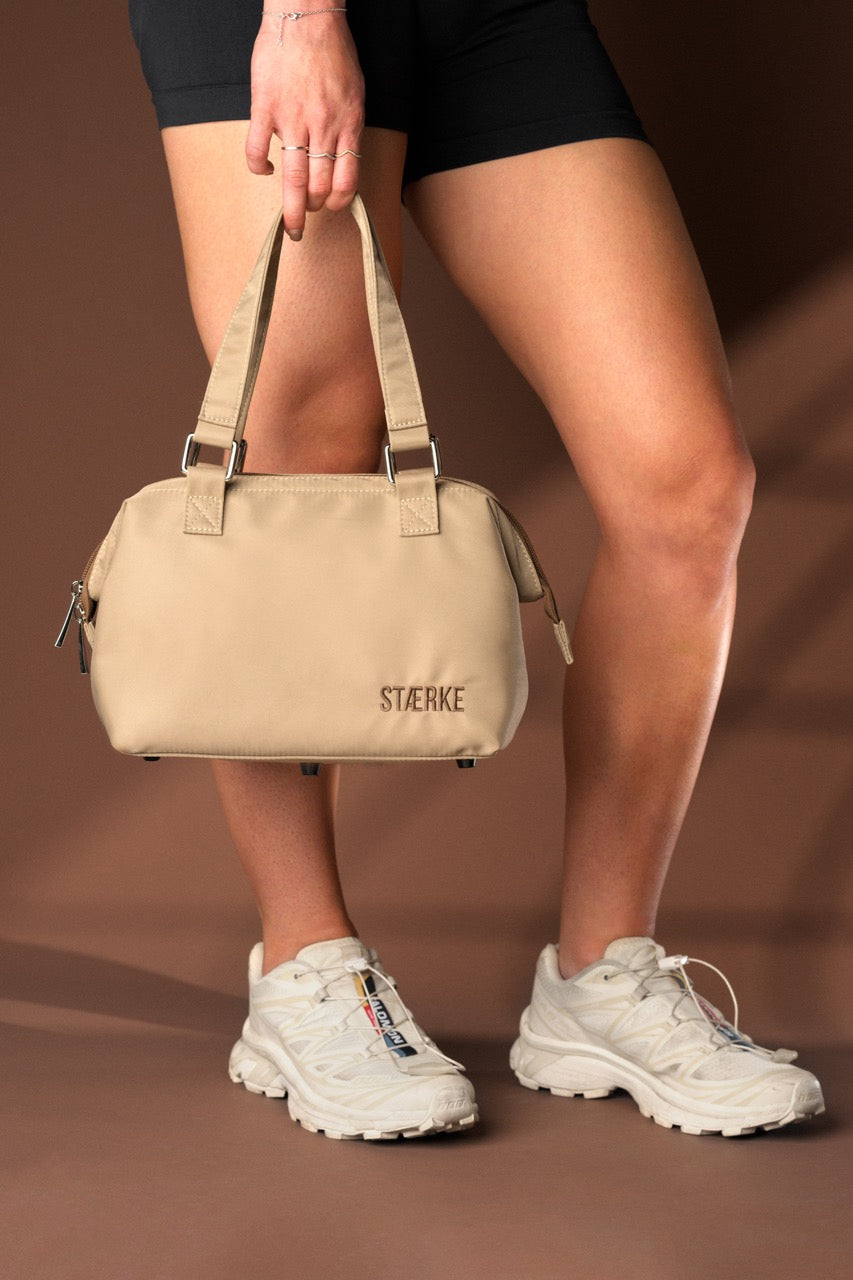 STÆRKE mini gym bag in beige recycled nylon, Scandinavian minimalist design, carried by model