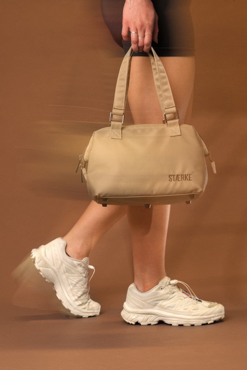 STÆRKE mini gym bag in beige recycled nylon, Scandinavian minimalist design, carried by model