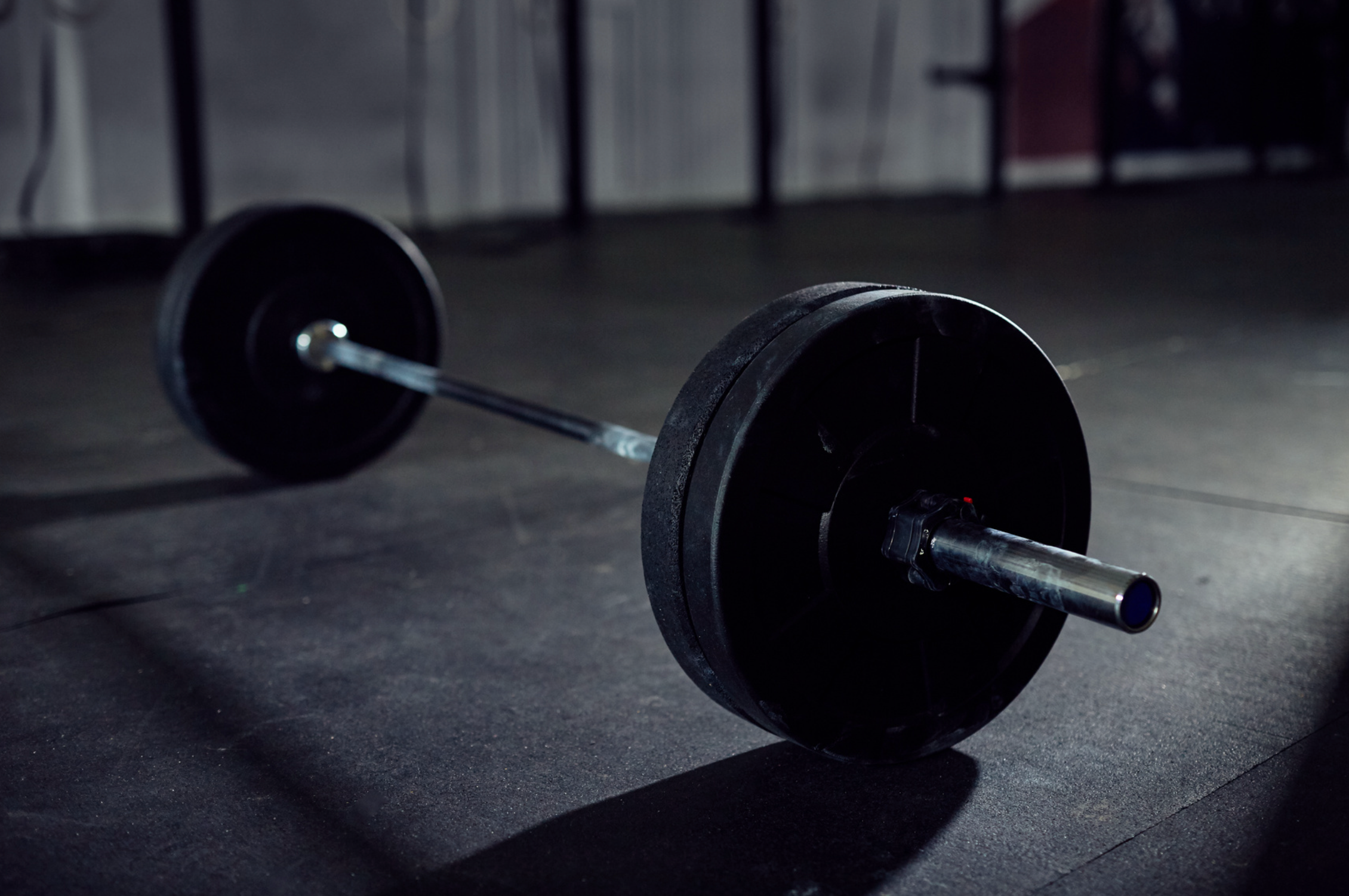 Olympic barbell on gym floor, fitness inspiration for STÆRKE gymwear